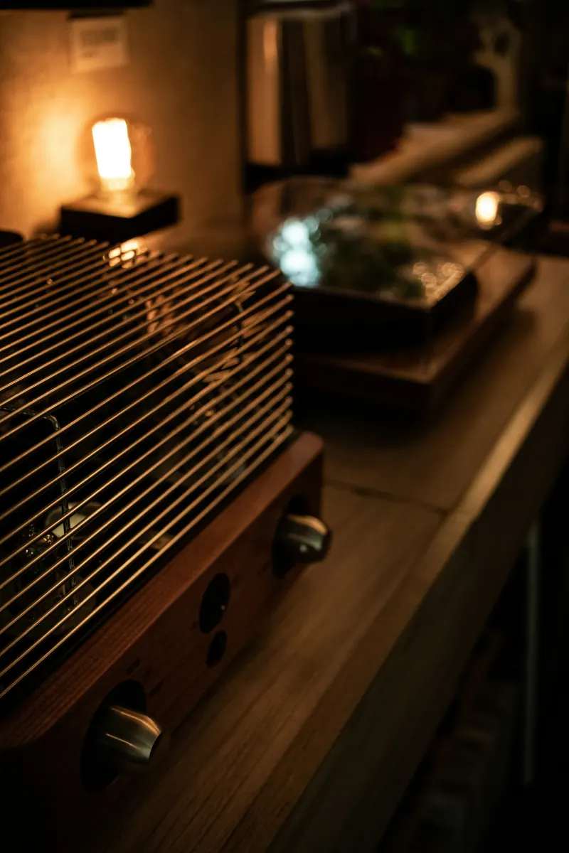 Tube amplifier with a wire cage and walnut front panel beside an amber filament lamp